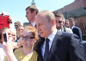 Vladimir Putin taking a selfie with a young girl outdoors