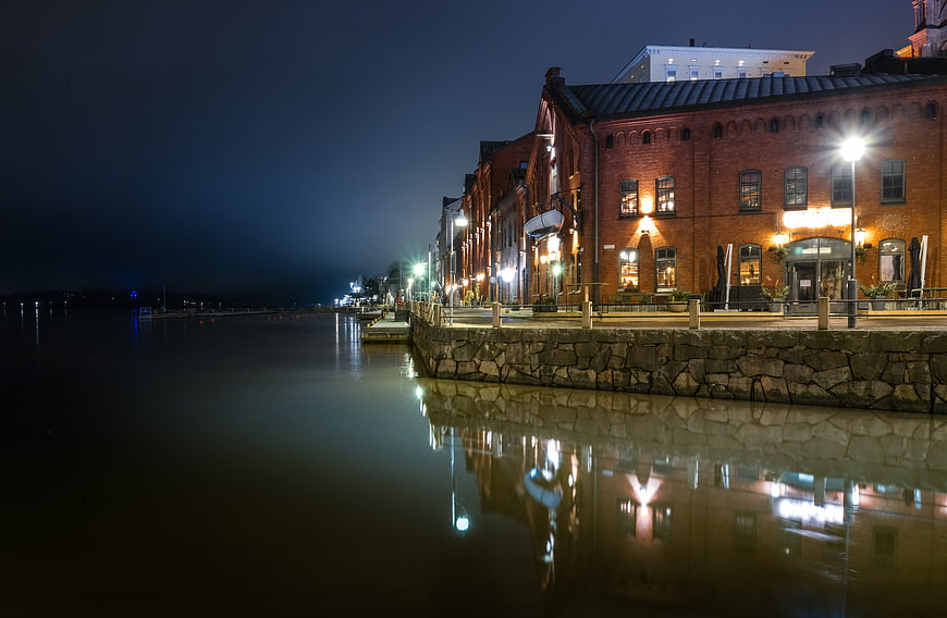 Illuminated historic brick buildings along Helsinki harbor at night