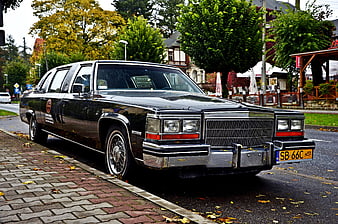 Classic black Cadillac limousine parked on wet street