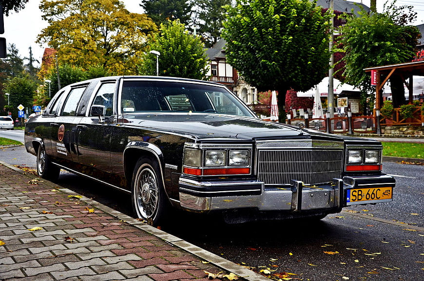 Classic black Cadillac limousine parked on wet street