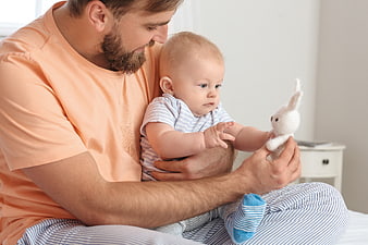 Father holding baby playing with stuffed bunny toy
