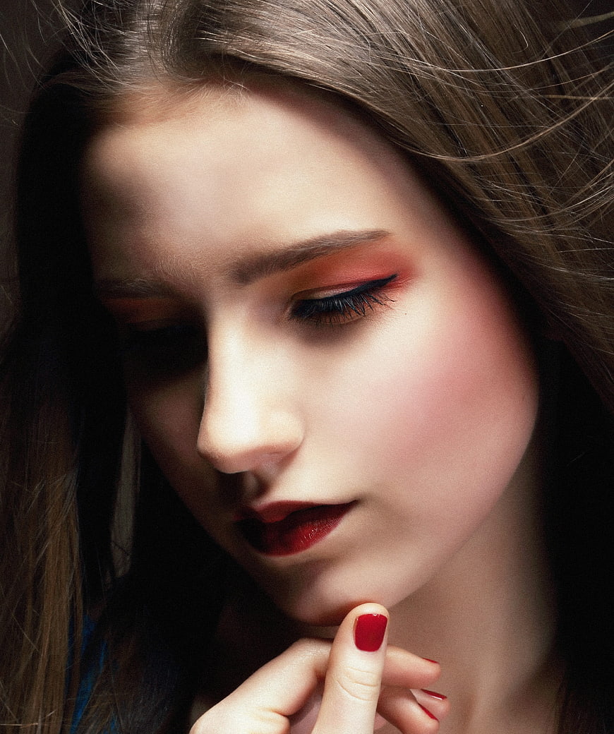 Close-up portrait of woman with red makeup and nail polish