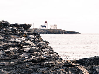 Lighthouse on rocky island with foreground coastal stones