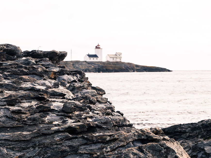 Lighthouse on rocky island with foreground coastal stones