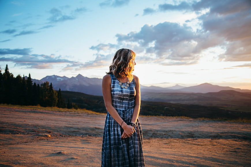 Woman in Tie-Dye Dress Standing in Mountain Landscape at Sunset