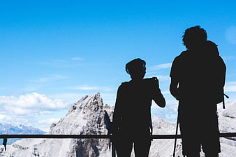 Silhouette of Hikers on Mountain Peak with Blue Sky