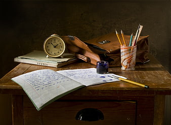 Vintage school desk with notebook, ink, and alarm clock