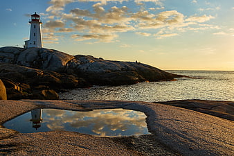 Lighthouse Reflection on Rocky Coast at Sunset