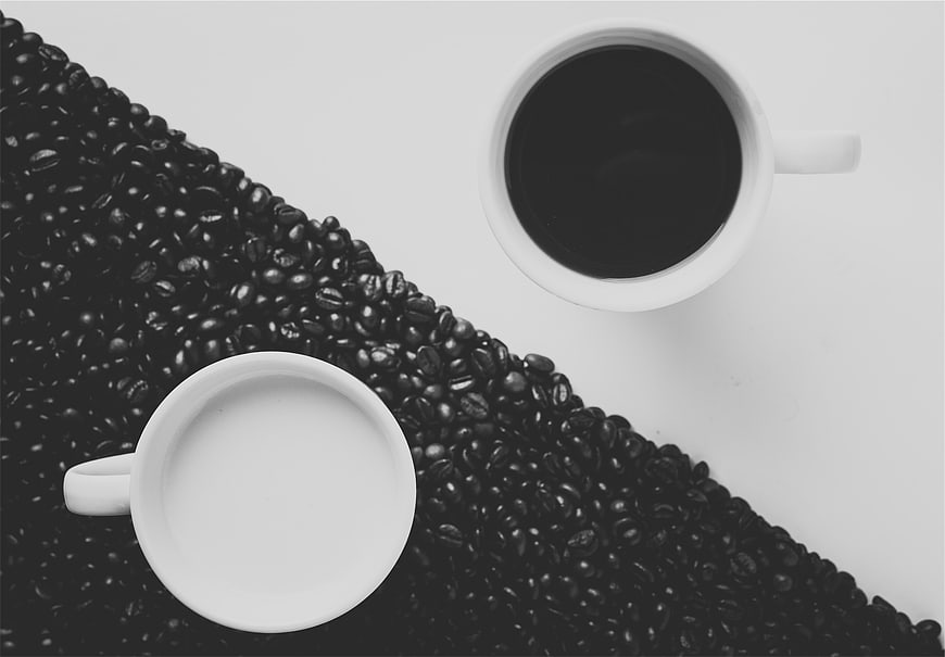 Black and white coffee beans and cups flat lay