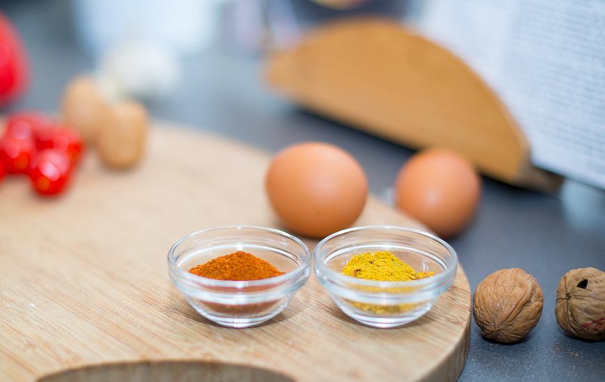 Spices, eggs, and walnuts on a wooden cutting board