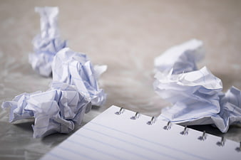 Crumpled paper balls and blank spiral notepad on a desk