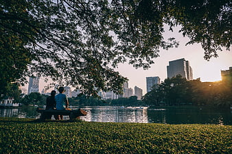 Couple Relaxing on Park Bench by Lake with City Skyline