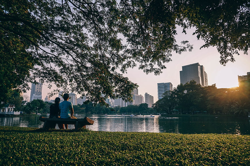 Couple Relaxing on Park Bench by Lake with City Skyline