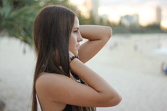 Young woman with long hair looking away on a beach at sunset
