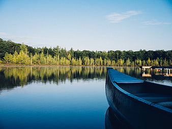 Blue canoe on calm lake with forest reflection