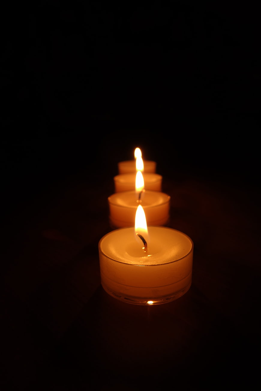 Row of lit tea light candles on black background