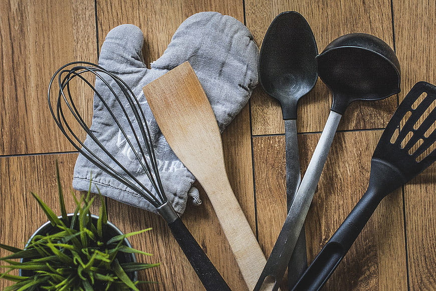 Flat lay of vintage kitchen utensils and oven mitt on rustic wood
