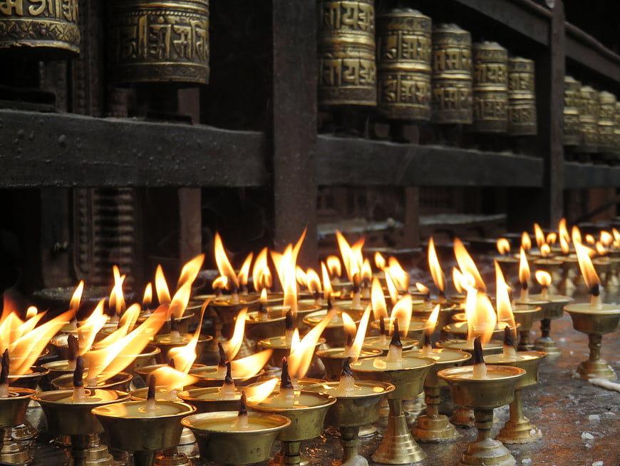 Rows of burning butter lamps and prayer wheels in a temple
