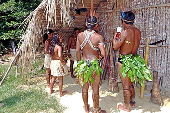 Indigenous Tribe Members in Traditional Attire Outside Hut
