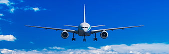 Commercial airplane approaching for landing against a bright blue sky