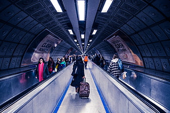 Commuters walking through London Underground escalator tunnel