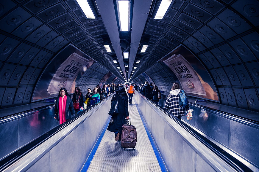 Commuters walking through London Underground escalator tunnel