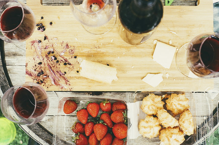 Overhead view of wine, cheese, strawberries, and cookies on a wooden board
