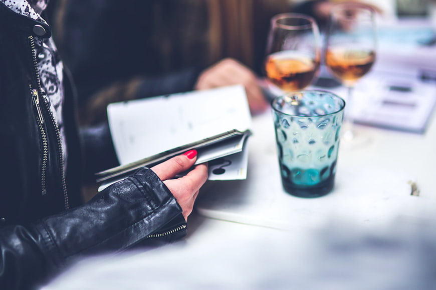 Woman in leather jacket holding menu at restaurant table