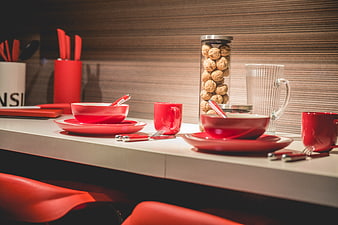 Modern red tableware set on white kitchen counter with walnuts