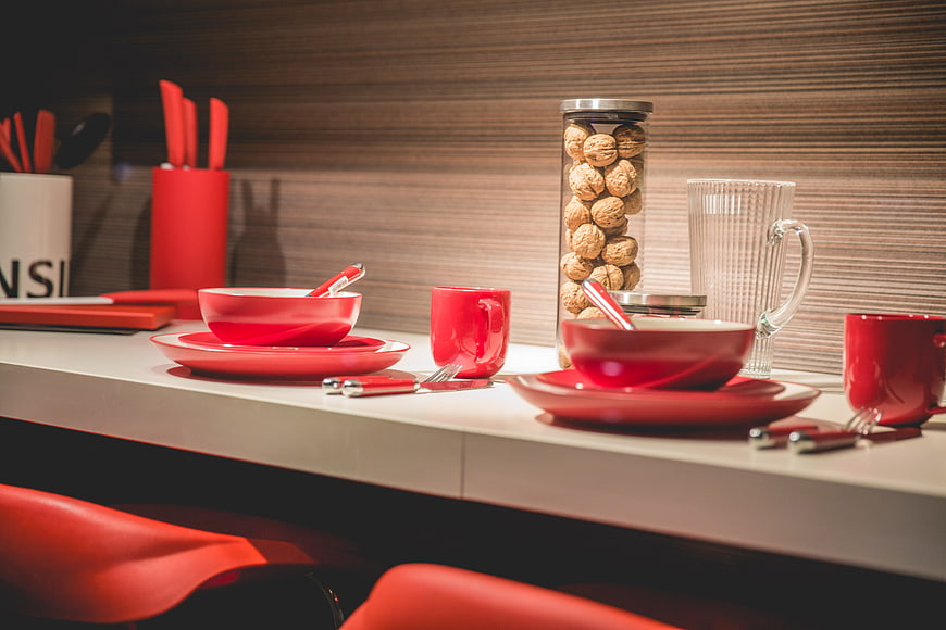 Modern red tableware set on white kitchen counter with walnuts