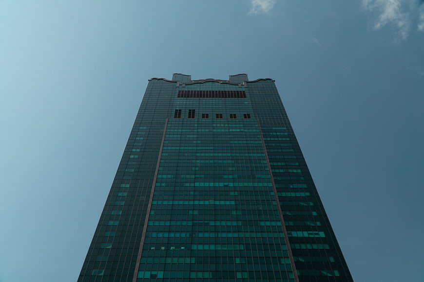 Low angle view of modern glass skyscraper against blue sky