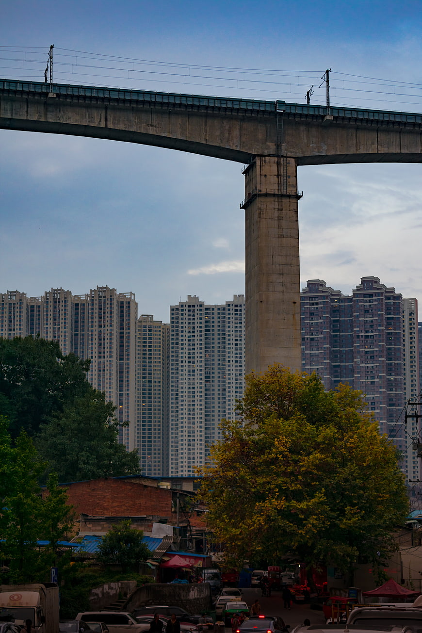 Elevated railway bridge over urban street with high-rise apartments