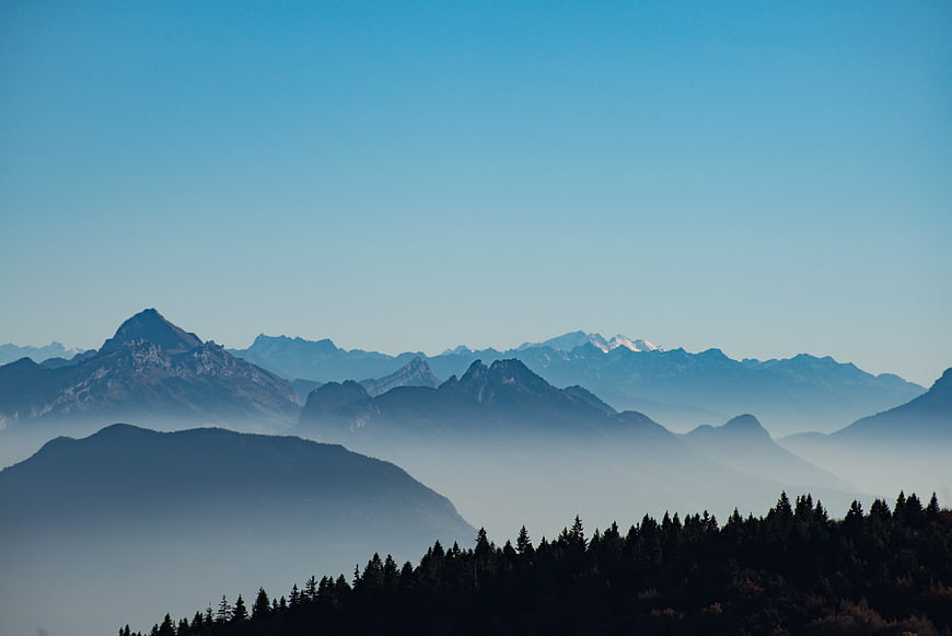 Misty Mountain Range with Forest Silhouette and Blue Sky