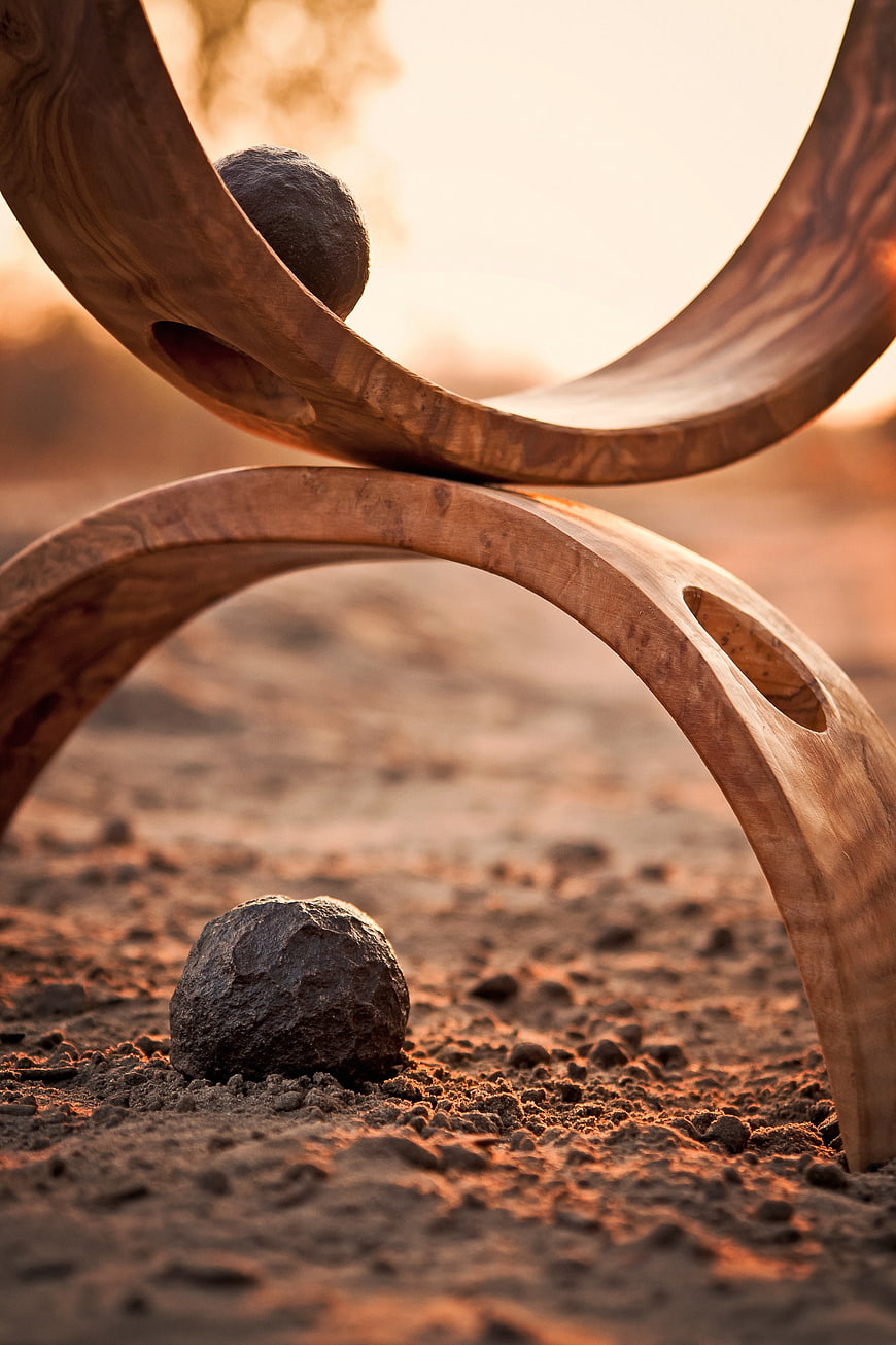 Abstract wooden sculpture with stones in desert landscape