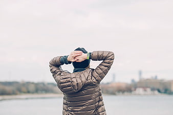 Person in Brown Puffer Jacket Looking at City Skyline
