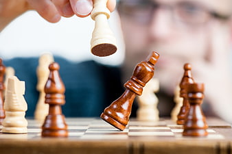 Hand capturing chess piece symbolizing strategy and victory