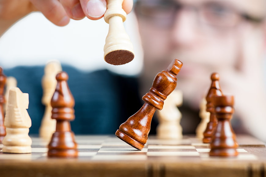 Hand capturing chess piece symbolizing strategy and victory