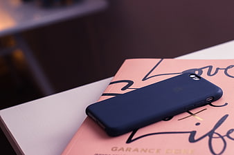 Blue smartphone case on pink book with calligraphy