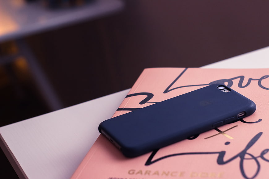 Blue smartphone case on pink book with calligraphy