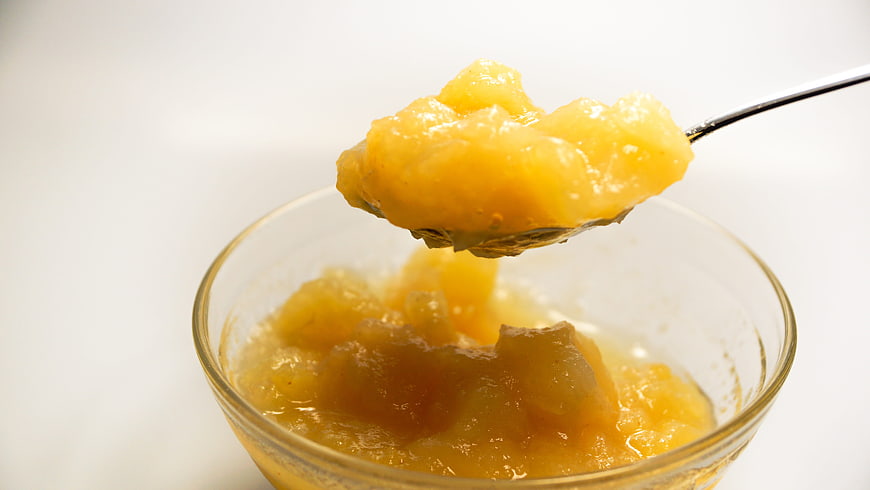 Chunky Applesauce in a Clear Glass Bowl with a Metal Spoon