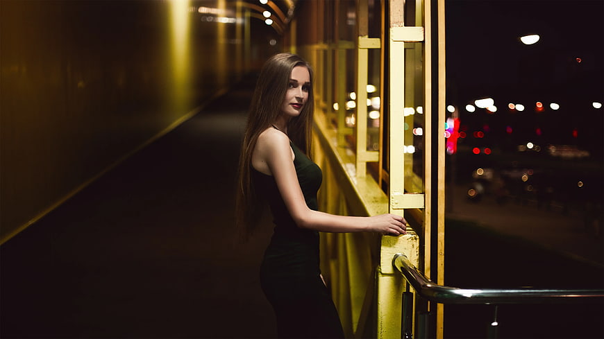Woman in Green Dress Leaning on Yellow Railing at Night