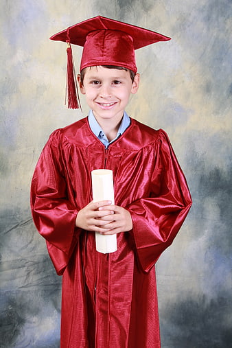 Happy young boy in red graduation gown holding diploma