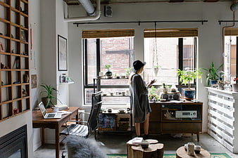Woman in hat standing in modern loft office with plants