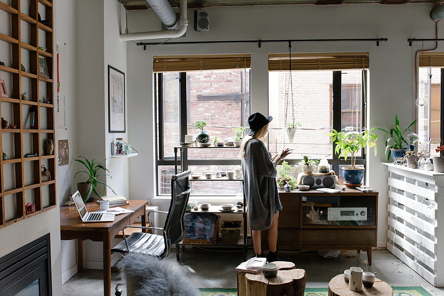 Woman in hat standing in modern loft office with plants