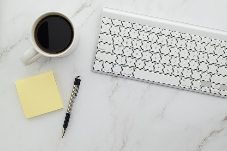 Minimalist workspace with coffee, keyboard, and sticky note