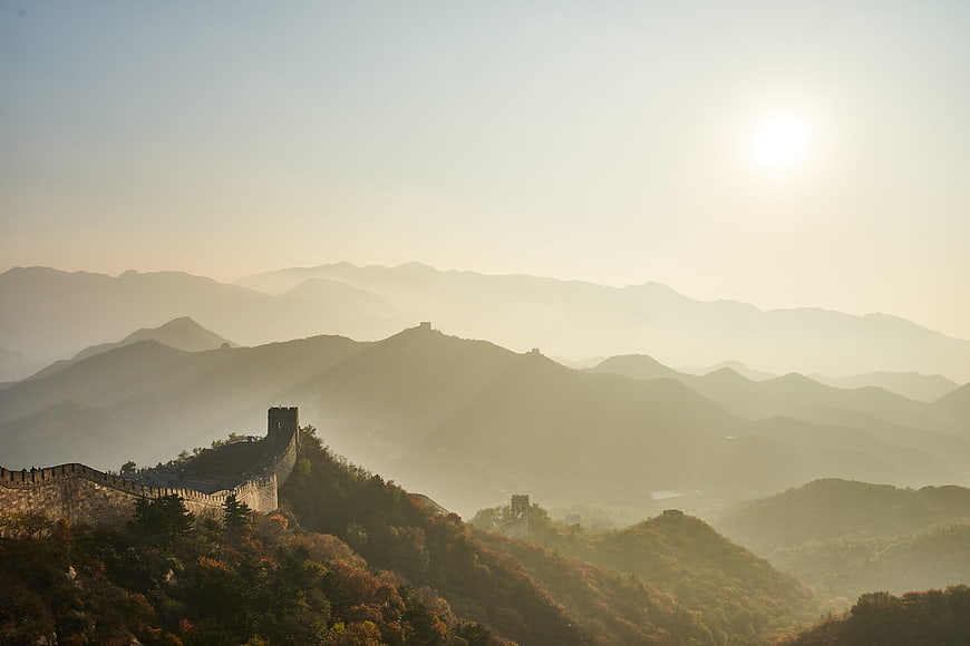 Great Wall of China winding through misty autumn mountains at sunrise