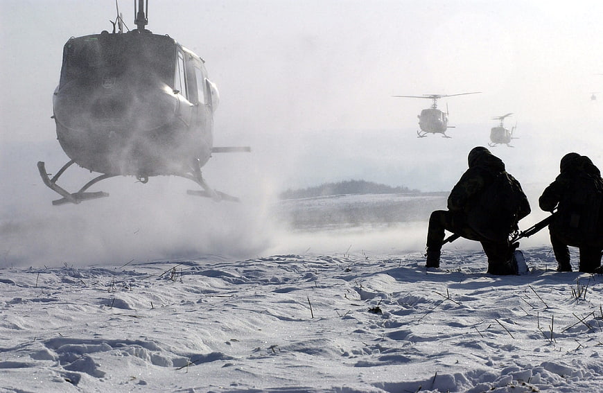 Military helicopters landing in snow with soldiers