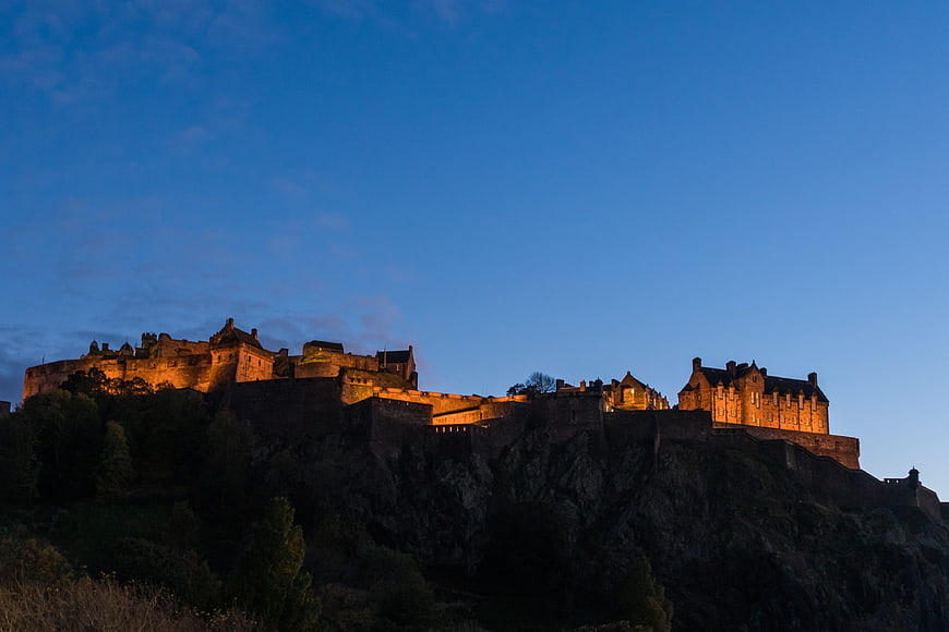 Edinburgh Castle illuminated at dusk on rocky crag