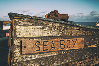 Weathered wooden boat named Sea Boy with rusty anchor