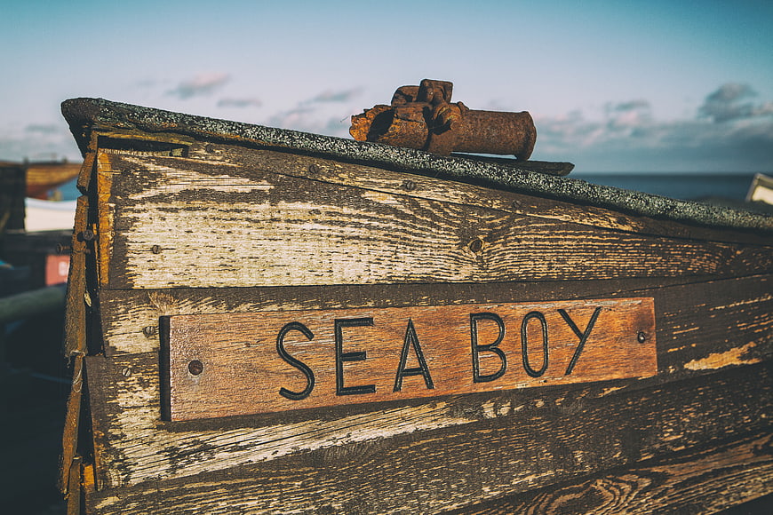Weathered wooden boat named Sea Boy with rusty anchor